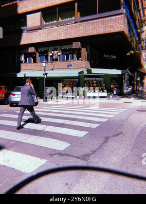 Madrid, Espagne. 1er juillet 2024 Une scène trépidante d'une rue de la ville métropolitaine, un homme d'affaires en costume d'affaires traverse la rue. Contraste des ombres. Banque D'Images