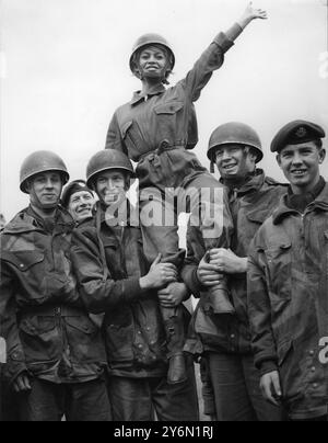 L'actrice française Brigitte Bardot en tenue de parachutiste s'envole sur les épaules de parachutistes britanniques réels. Banque D'Images