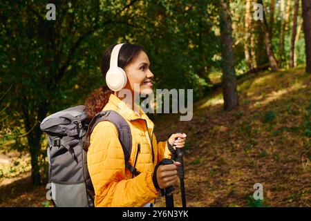 Une jeune femme afro-américaine fait des randonnées à travers une forêt d'automne colorée, incarnant un mode de vie actif. Banque D'Images