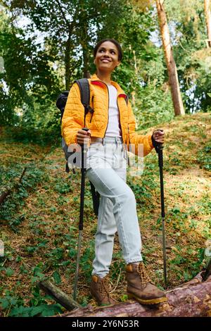 Une jeune femme afro-américaine fait des randonnées en toute confiance à travers une forêt d'automne colorée, embrassant la beauté de la nature. Banque D'Images