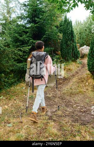 Une jeune femme afro-américaine fait des randonnées à travers une forêt vibrante, embrassant la beauté de l'automne et l'aventure. Banque D'Images