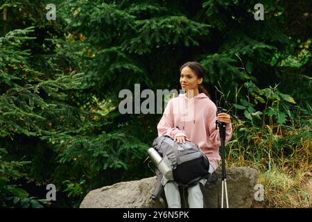 Une jeune femme prend un moment pour se reposer tout en faisant une randonnée dans une belle forêt d'automne entourée par la nature. Banque D'Images