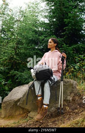 Au cœur de l’automne, une jeune femme prend un moment pour profiter de la nature tout en faisant une randonnée dans la forêt luxuriante. Banque D'Images