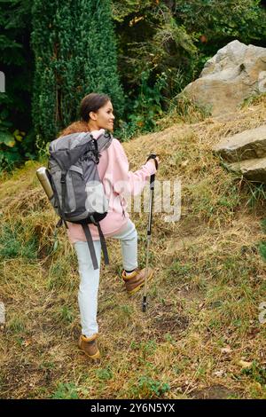 Une jeune femme afro-américaine fait des randonnées à travers une forêt d'automne colorée, embrassant la nature et l'aventure. Banque D'Images