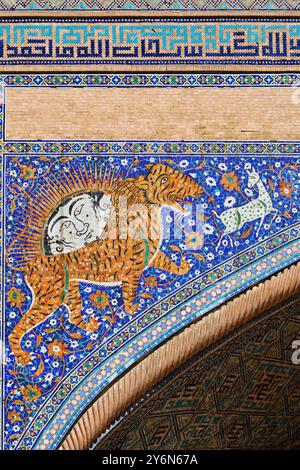 Samarcande, Ouzbékistan - 10 septembre 2024 : façade de la madrassah Sher Dor sur la place Registan. Panneau de mosaïque célèbre avec image de lion ensoleillée Banque D'Images