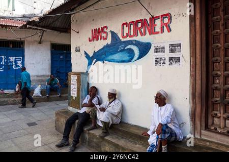 Les hommes de la région se détendent à Jaws Corner, au cœur de Stone Town, Zanzibar, où vous pourrez admirer le Street art dynamique et la vie quotidienne dans cet endroit historique. Banque D'Images