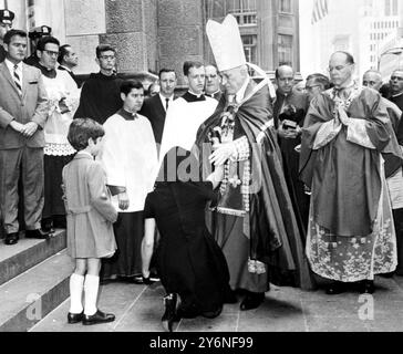 New York : alors que John Kennedy Jr, regarde (à gauche) sa mère, Mme Jacqueline Kennedy, s'agenouiller devant Richard Cardinal Cushing devant la cathédrale St Patrick ici après la messe de requiem pour son beau-sénateur Robert Kennedy. À droite, Mgr Terence J. Cooke. 10 juin 1968 Banque D'Images