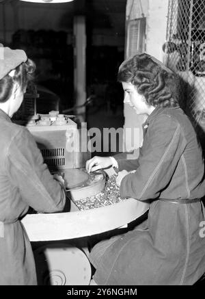 La production militaire à grande échelle de l'arsenal de Woolwich à Londres est toujours poursuivie afin de maintenir nos défenses. Cependant, une grande partie de l'énergie de la guerre a été détournée à des fins plus pacifiques comme la production de médailles pour les militaires et civils, mais la vue la plus discrète est les hommes qui tournent le porte-rouge à lèvres et les filles qui produisent des étuis à balles. Mme B. Hastings, jolie opératrice de l'une des machines de presse et de rotation pour .380 balles Banque D'Images