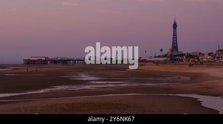 Le crépuscule tombe sur une plage tranquille, avec une jetée et une grande roue silhouette sur le ciel du soir. Banque D'Images