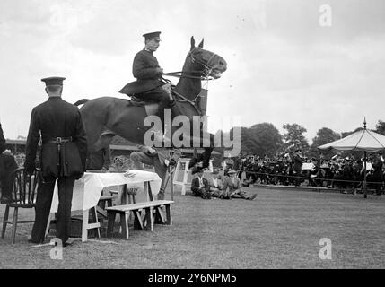 Richmond Horse Show. J Buckland sur une jument brune, sautant par-dessus une table de dîner posée pour le dîner, avec des invités assis et debout autour d'une table fumant et buvant sur les caractéristiques de l'exposition de police montée. 9 juin 1921 Banque D'Images