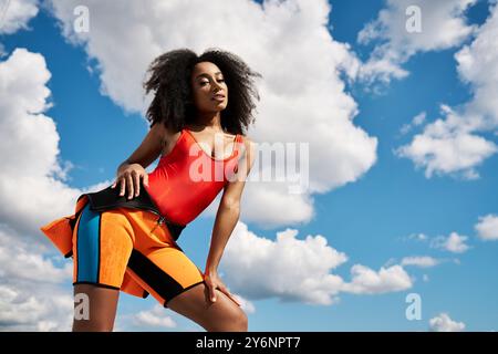 Une belle jeune femme afro-américaine présente des vêtements tendance sous un ciel lumineux. Banque D'Images