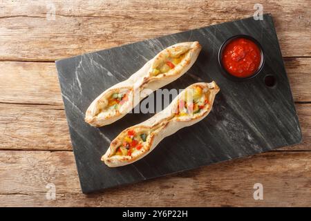 Délicieuse pizza sorrentine alle verdure avec fromage et légumes poivre, tomates, artichaut, courgettes cuites dans un four à bois gros plan sur un sla Banque D'Images