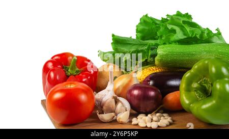 Un assortiment vibrant de légumes biologiques frais, y compris laitue, tomate, poivre, ail, et courgettes, affichées sur une planche à découper en bois, symbole Banque D'Images