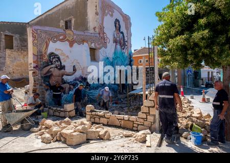 Ouvriers construisant un mur de pierre à côté d'une murale colorée dans le vieux centre-ville de Paphos, Paphos, Chypre. Banque D'Images