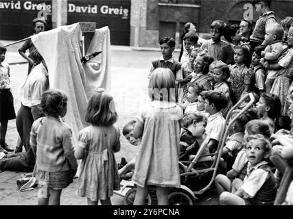 Les enfants de Mitre St , Waterloo , Londres , ont décidé qu'un ajout agréable à la rue serait un spectacle de Punch et Judy , qu'ils ont fait à partir de morceaux de ferraille et de boîtes orange . Les cinq enfants qui ont réalisé et organisé le spectacle sont Fred Wilson , Will Webb , qui fait aussi des commentaires , Dave Eason , Raymond Jordan et Will Bridges . L'image montre le public enfantin du spectacle Punch et Judy. 11 août 1950 Banque D'Images