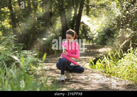 Fit femme sportive à l'aide d'un smartphone dans un brassard, à l'extérieur. Banque D'Images