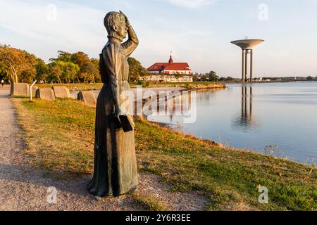 Statue de l'écrivaine suédoise Selma Lagerlöf (1858-1940) à Landskrona. La figure regarde au-dessus du Öresund, tenant un livre dans sa main droite. Durant son séjour à Landskrona (1885-1895), elle écrit son premier roman Gösta Berling. Son œuvre la plus célèbre est publiée en 1907 : The Wonderful Journey of Little Nils Holgersson with the Wild Oies. En 1909, elle a été la première femme à remporter le prix Nobel de littérature et en 1914, elle a été la première femme à être admise à l'Académie suédoise. Fröjdenborg, Landskrona kommun, Skåne, Suède Banque D'Images