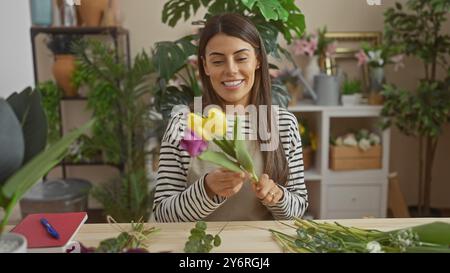 Femme hispanique souriante arrangeant des tulipes colorées à la maison, créant un cadre intérieur vibrant. Banque D'Images