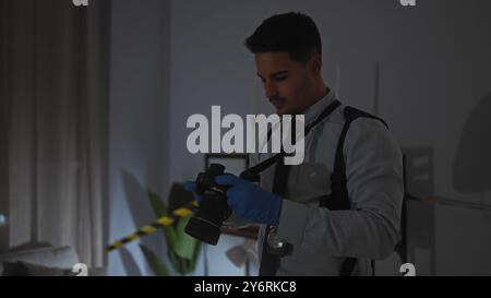 Un jeune homme hispanique examine des preuves avec une caméra sur une scène de crime à l'intérieur. Banque D'Images