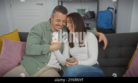 Un couple souriant profite d'un moment d'amour sur un canapé dans un salon confortable, indiquant une relation heureuse. Banque D'Images