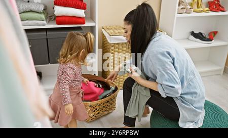 Une femme et une jeune fille organisent des vêtements dans un dressing moderne et bien éclairé, partageant un moment de lien familial. Banque D'Images