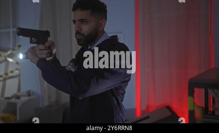 L'homme hispanique armé d'un pistolet enquête sur une scène de crime intérieure faiblement éclairée, affichant tension et concentration. Banque D'Images