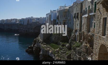 Vue de polignano une jument en italie, présentant des bâtiments historiques en pierre perchés sur des falaises au-dessus de la mer bleue sereine par une journée ensoleillée. Banque D'Images