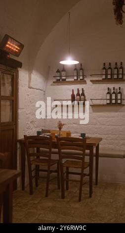 Un restaurant italien intime à l'intérieur avec une configuration de table confortable, des murs de briques rustiques, des chaises en bois, des étagères de bouteilles de vin et un éclairage tamisé créant Banque D'Images