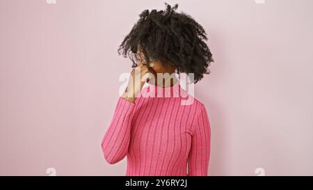 Une femme noire se pince le nez à l'intérieur sur un fond rose, suggérant une mauvaise odeur. Banque D'Images