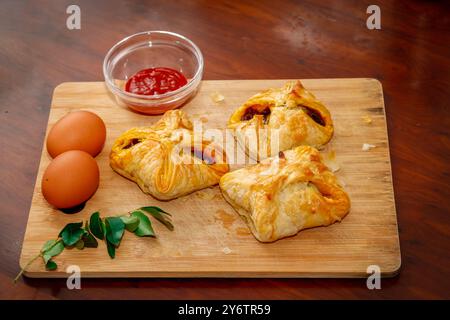 Gros plan sur une planche à découper en feuilletés aux œufs savoureux de style Kerala avec sauce tomate, feuilles de curry et oeuf. Fond en bois Banque D'Images