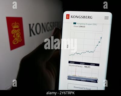 Dans cette illustration photo, une personne tient un téléphone portable avec la page Web de la société norvégienne Kongsberg Gruppen ASA devant le logo. Banque D'Images