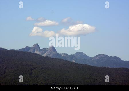 Les pentes boisées des montagnes de la rive nord de la chaîne côtière, et les sommets jumeaux des Lions, près de Vancouver, Colombie-Britannique, Canada. Banque D'Images