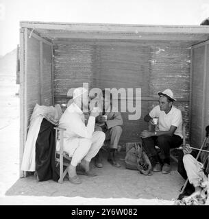 L'HOMME DANS LE CRÂNE Cap Jordan : Une figurine blanche dans un crâne dégustez un verre rafraîchissant avec l'acteur Peter O'Toole, au centre, et le réalisateur David Lean, à droite, dans une cabane installée au cœur du désert jordanien, où se déroule actuellement le tournage de Lawrence d'Arabie. L'homme dans la casquette du crâne ? Sir Alec Guinness, qui joue le prince Feisal dans le film. Peter O'Toole sera vu dans le rôle de Lawrence et le film est produit par Sam Spiegel qui, avec Sir Alec et Mr Lean a réalisé le pont sur la rivière Kwai. 9 AOÛT 1961 Banque D'Images