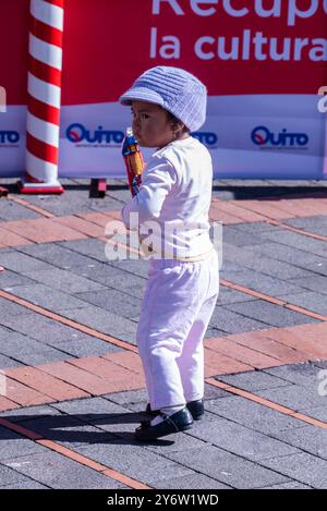 Une jeune fille de 3-5 ans transporte seule un paquet de craquelins sur un trottoir à Quito, en Équateur. Banque D'Images