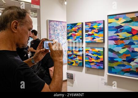 New York, NY, États-Unis. 26 septembre 2024. La Fall Affordable Art Fair, qui se déroule jusqu'en septembre 29, a ouvert ses portes dans le Metropolitan Pavilion avec des galeries des États-Unis et d'outre-mer montrant l'art moderne et contemporain dans de nombreux médias. Un visiteur photographie des collages d'Elllen Globokar sur le stand de l'Agora Gallery de New York. Crédit : Ed Lefkowicz/Alamy Live News Banque D'Images