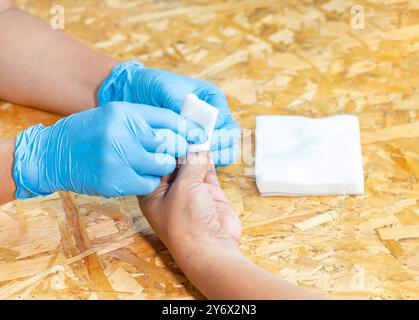 Gros plan médecin appliquant un bandage sur le doigt de l'homme à l'hôpital. Banque D'Images
