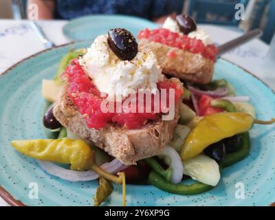 Chania, Grèce. 12 septembre 2024. Les Dakos sont servis dans une assiette. L'entrée crétoise se compose de tomates, d'herbes et de feta sur paximadi, un pain de longue durée cuit plusieurs fois. Crédit : Alexandra Schuler/dpa/Alamy Live News Banque D'Images