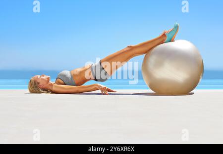 Femme, fitness ou entraînement avec ballon d'exercice pour les étirements, l'entraînement en plein air ou l'équilibre au bord de la piscine. Jeune, femme ou muscle abdominal Banque D'Images