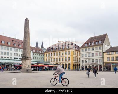 Wuerzburg, Allemagne - 19 octobre 2023 : cycliste chevauchant la place du marché dans le centre-ville avec la fontaine de l'obélisque Banque D'Images