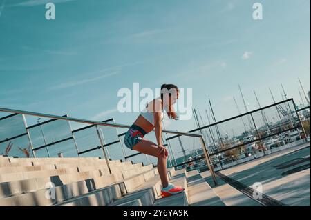 Habitudes saines. Pleine longueur de belle jeune femme dans des vêtements de sport se relaxant tout en faisant de l'exercice à l'extérieur Banque D'Images