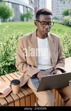 Jeune homme noir travaillant sur un ordinateur portable à l'extérieur Banque D'Images