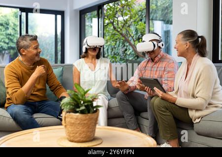 Profiter de la réalité virtuelle, amis seniors divers utilisant des casques VR ensemble à l'intérieur, à la maison Banque D'Images