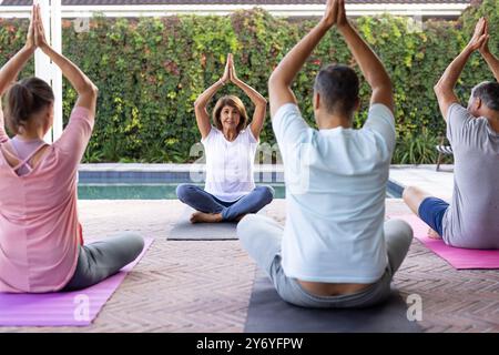 Pratiquer le yoga, des amis âgés divers assis sur des tapis à l'extérieur, profiter de l'exercice de groupe, à la maison Banque D'Images