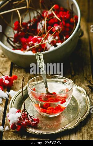 baies fraîches d'une guelder-rose dans une tasse en verre sur une table en bois. style rustique. l'image est teintée Banque D'Images