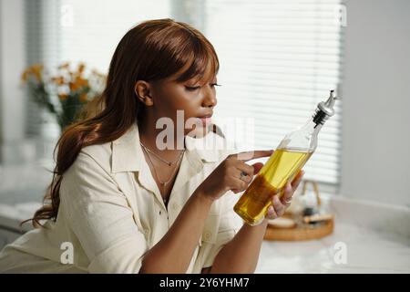 Examiner la bouteille d'huile d'olive dans la cuisine éclairée par le jour Banque D'Images