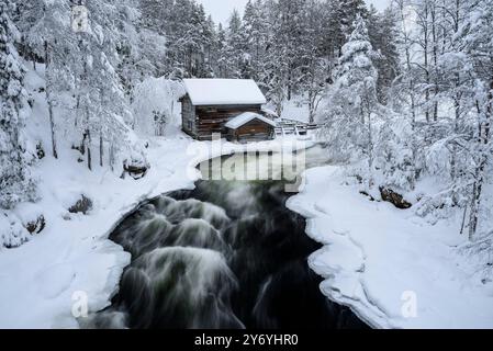 Ancien moulin de Myllykoski, couvert de neige en hiver, à côté des rapides de la rivière Kitkajoki dans le parc national d'Oulanka (Juuma Kuusamo Laponie Finlande) Banque D'Images
