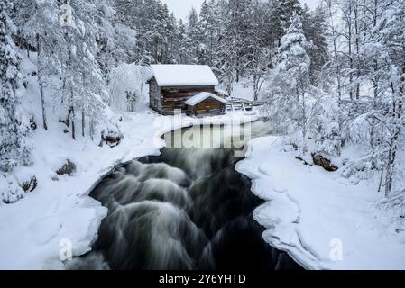 Ancien moulin de Myllykoski, couvert de neige en hiver, à côté des rapides de la rivière Kitkajoki dans le parc national d'Oulanka (Juuma Kuusamo Laponie Finlande) Banque D'Images