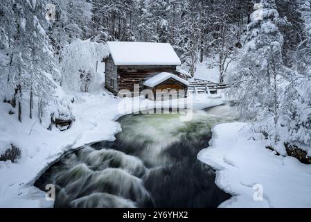 Ancien moulin de Myllykoski, couvert de neige en hiver, à côté des rapides de la rivière Kitkajoki dans le parc national d'Oulanka (Juuma Kuusamo Laponie Finlande) Banque D'Images