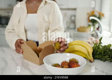 Préparation du rambutan frais tout en maintenant la boîte ouverte Banque D'Images