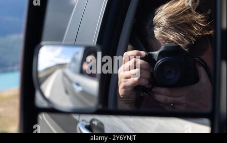 Femme se photographiant depuis un rétroviseur de véhicule Banque D'Images